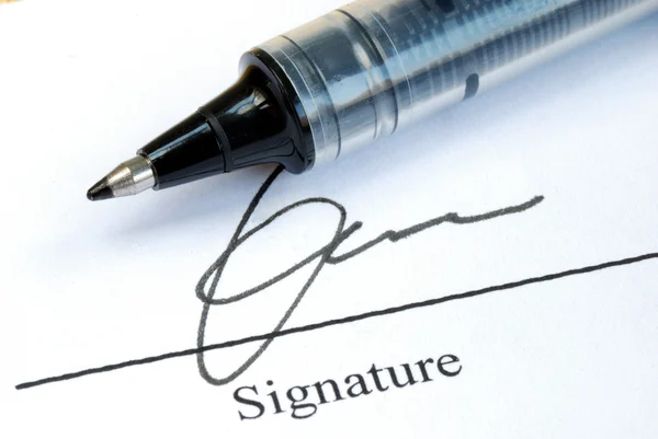 Unterschreiben Sie den Namen mit einem Stift auf einem Papier lizenzfreie Stockfotos
