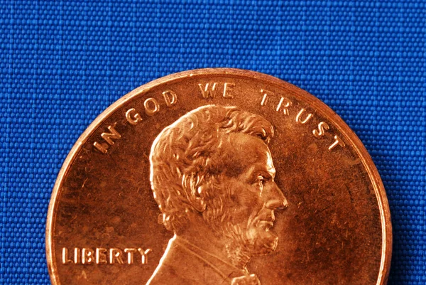 En Dios confiamos desde el centavo aislado en azul —  Fotos de Stock