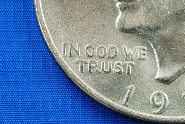 Em Deus Confiamos da moeda de dólar isolada em azul — Fotografia de Stock