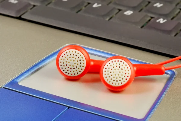 Piros fülhallgató-ra egy laptop koncepció zene letölt és kalózkodás — Stock Fotó