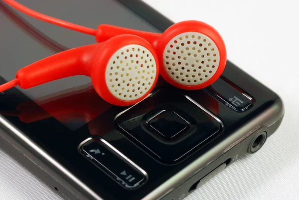 Κόκκινο ακουστικά σε ένα mp3 player έννοιες της κατεβάσετε μουσική και πειρατεία — Φωτογραφία Αρχείου