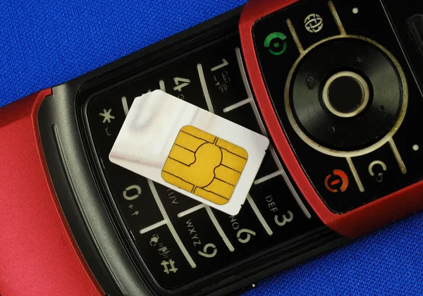Cellular phone with a SIM card isolated on blue — Stock Photo, Image