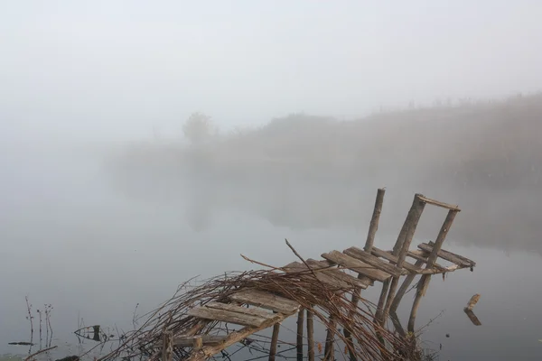 A ponte no rio na névoa — Fotografia de Stock