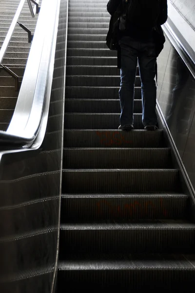 Człowiek przesuwa się w górę schodami ruchomymi — Zdjęcie stockowe