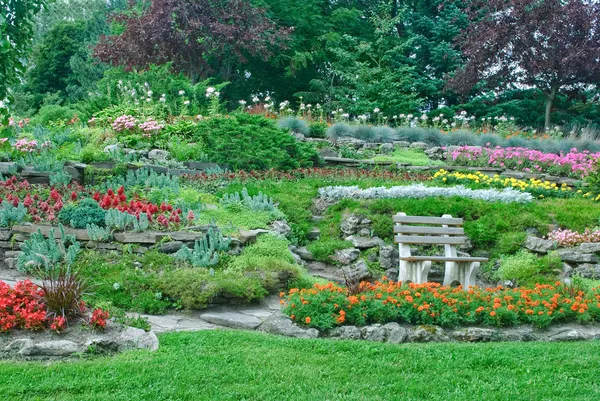 Garten mit Blumenbeeten, Zierpflanzen im Sommerpark lizenzfreie Stockfotos