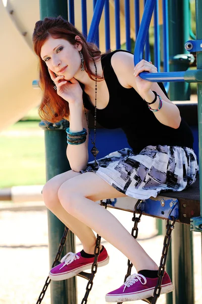 Young teen girl in skirt on playground equipment — Stock Photo, Image
