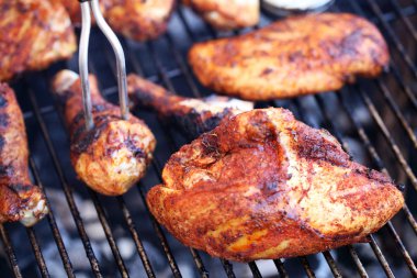 Barbecue chicken cooking on grill with fork clipart