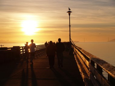 silhouette on pier at sunset clipart