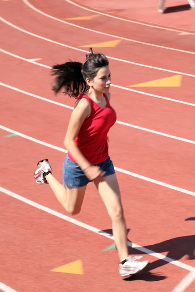 Giovane ragazza latina in esecuzione su pantaloncini da pista top rosso — Foto Stock