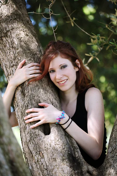 Jonge Kaukasische tiener meisje in boom glimlachen — Stockfoto