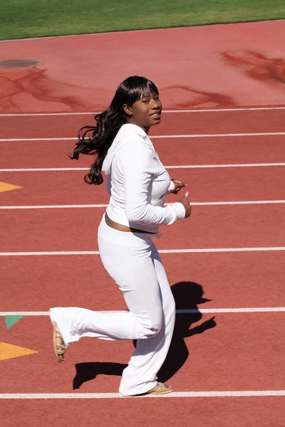 Young black woman white sweats running on track — Stock Photo, Image