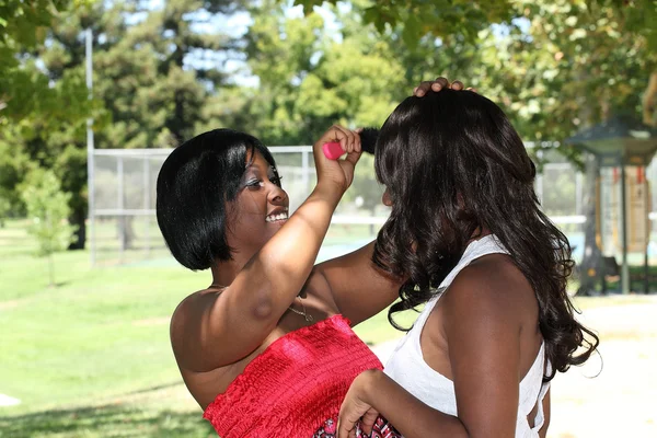 Jeune femme noire brossant les cheveux d'un autre à l'extérieur — Photo