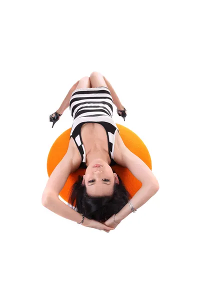 Молодая американка азиатского происхождения, лежащая на оранжевом стуле — стоковое фото