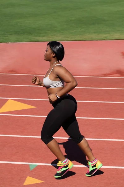 Llenita mujer negra corriendo al aire libre en pista — Foto de Stock