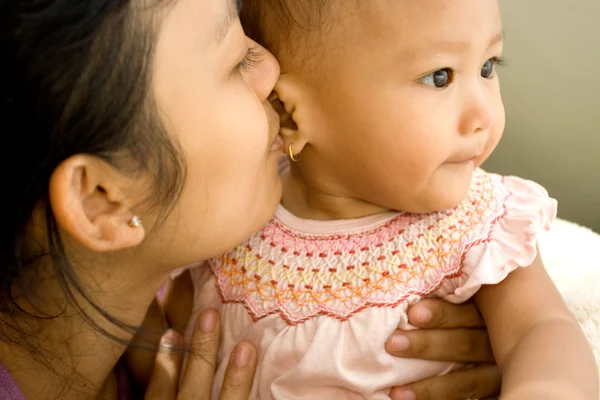 Азиатская мама целует ребенка — стоковое фото