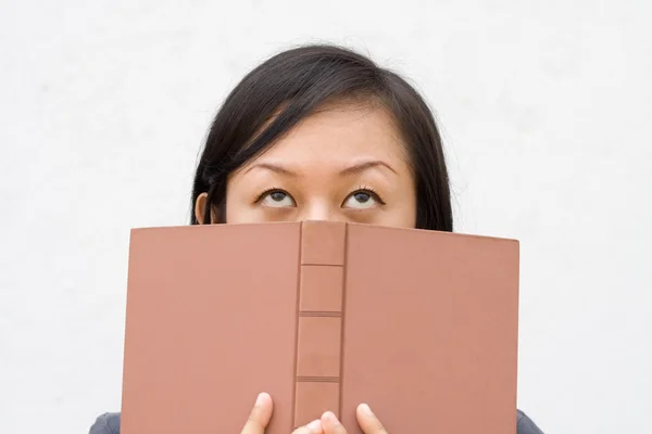 Flicka som täcker ansiktet med bok — Stockfoto