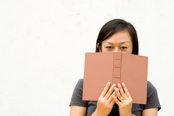 Chica cubierta de la cara con libro — Foto de Stock