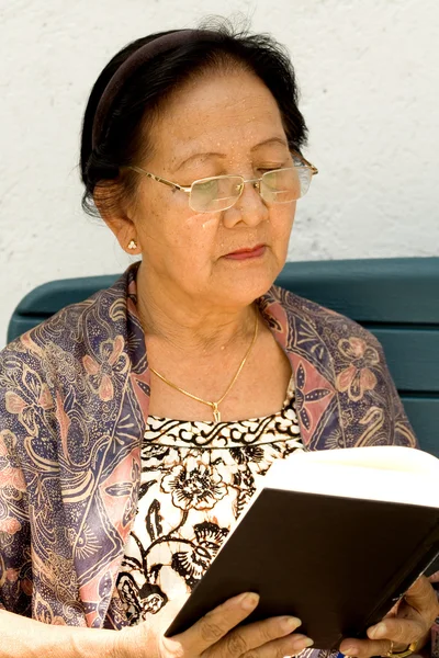 Aisan ηλικιωμένη γυναίκα διαβάζοντας ένα βιβλίο — Φωτογραφία Αρχείου