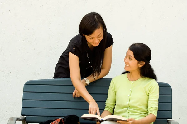 Female students discussing a book — Stock Photo, Image