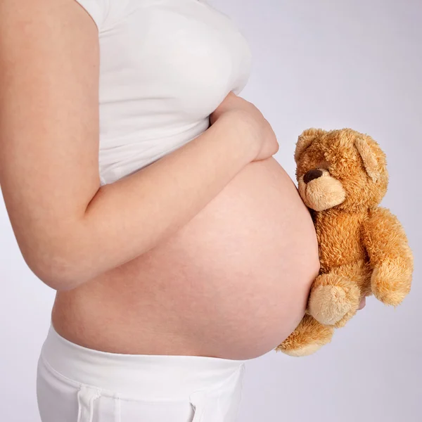Urso de pelúcia e barriga grávida — Fotografia de Stock
