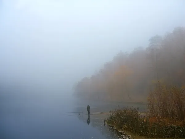 En fiskare på en dimmig sjö — Stockfoto