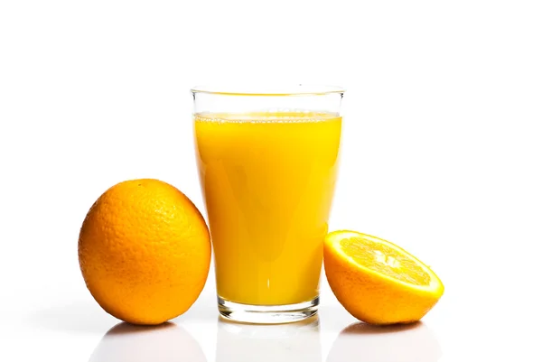 Ett glas apelsinjuice och apelsiner på vit bakgrund. — 图库照片