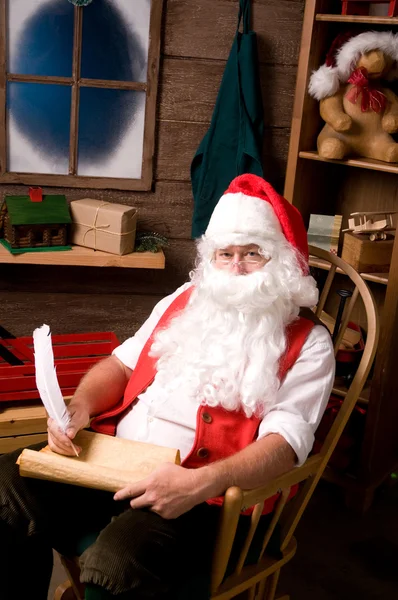 Santa claus in workshop met lijst — Stockfoto