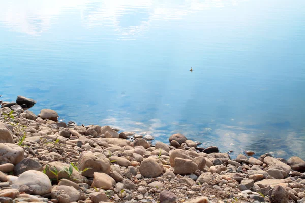 stock image Rocky shore and calm water surface