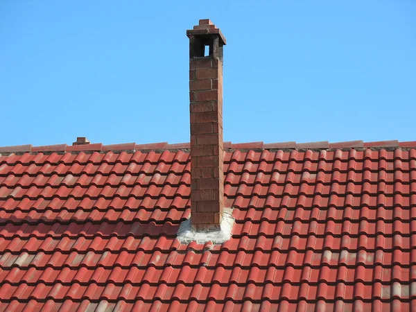 Труба из красного кирпича на черепичной крыше — стоковое фото