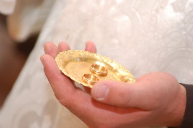 Priest holding wedding rings on the palm clipart
