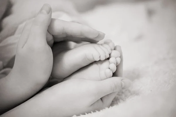 Feet and mothers hands — Stock Photo, Image