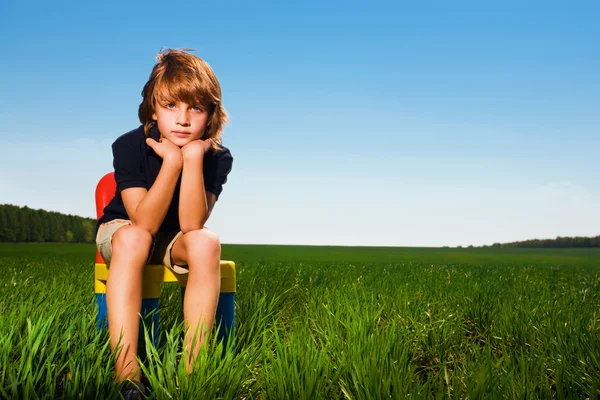 Jongen op stoel in veld — Stockfoto