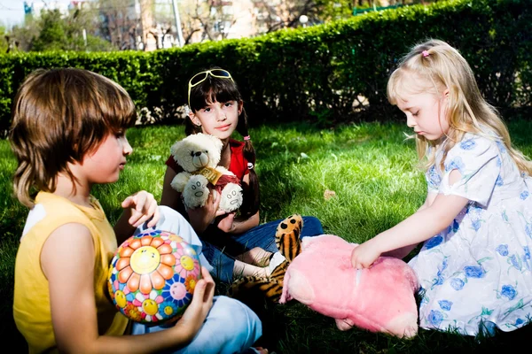 Chicas y chico con juguetes en la hierba —  Fotos de Stock