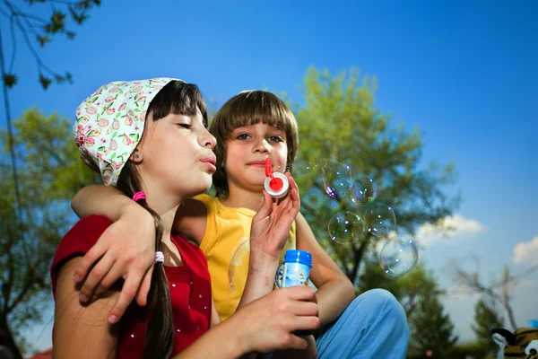 Menina com bolhas de sabão e menino — Fotografia de Stock
