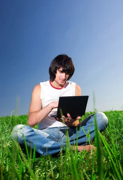 Jongen met laptop op gras — Stockfoto