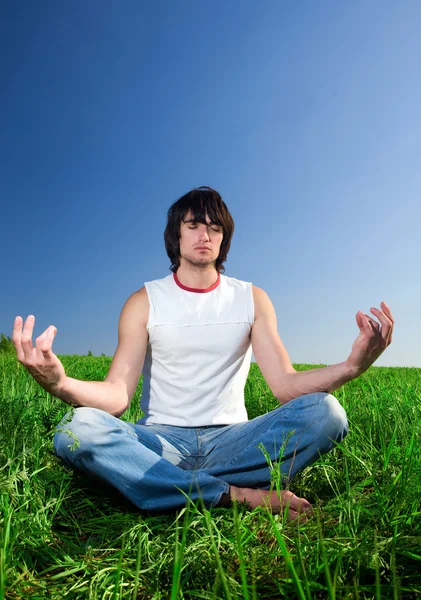 Мальчик медитирует на зеленой траве Стоковое Фото