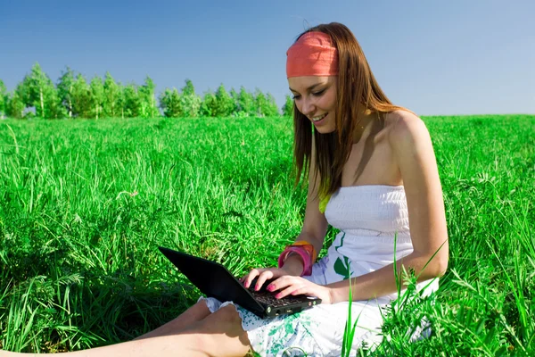 Menina com laptop na grama — Fotografia de Stock