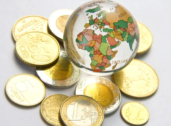 Мировой шар и разные монеты — стоковое фото