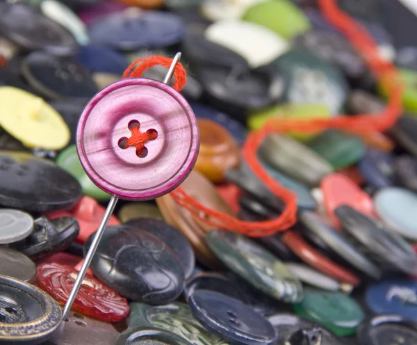 Sewing needle with buttons on background — Stock Photo, Image