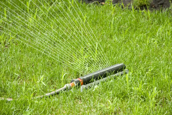 Irrigation sprinkler watering grass — Stock Photo, Image