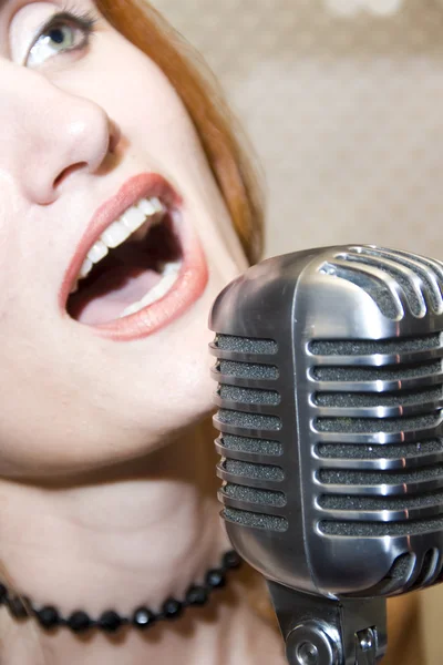 Woman singing into microphone — Stock Photo, Image