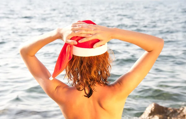 Mujer en sombrero de Navidad mirando al mar — Foto de Stock