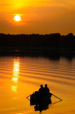 Fishermen in boat at sunset clipart