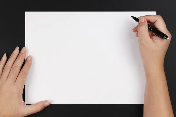 En kvinnas hand med en penna och papper — Stockfoto