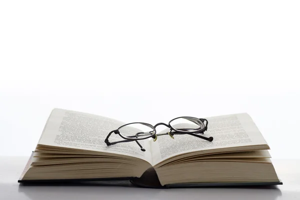 Öppen bok med glasögon — Stockfoto