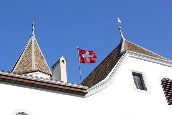 ニヨン城、スイス連邦共和国の屋根の上に浮かぶスイスの旗 — ストック写真