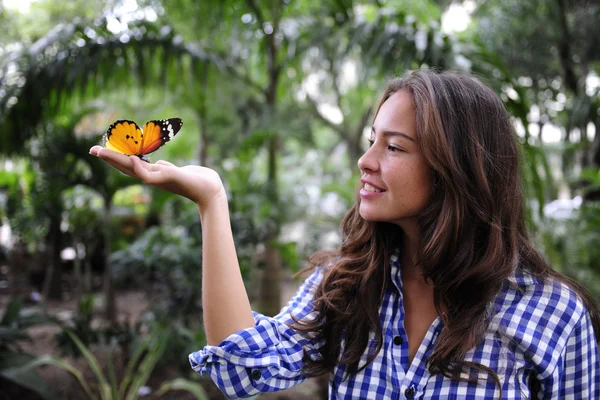 Schmetterling sitzt auf der Hand einer jungen Frau — Stockfoto