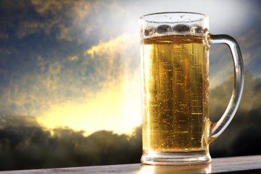 Glass of beer at sunset clipart