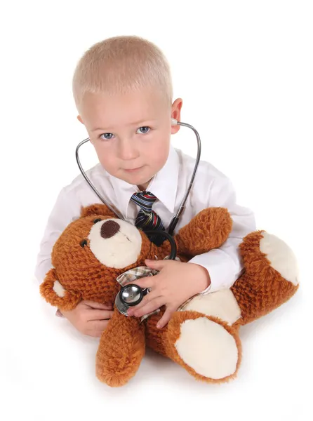 Kind gibt sich mit Teddybär als Arzt aus Stockbild