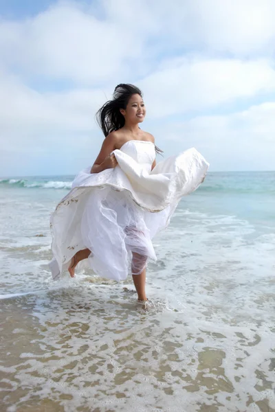 Braut läuft im Brautkleid durch den Ozean — Stockfoto